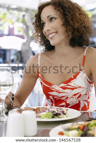 Happy beautiful woman eating meal at outdoor cafe