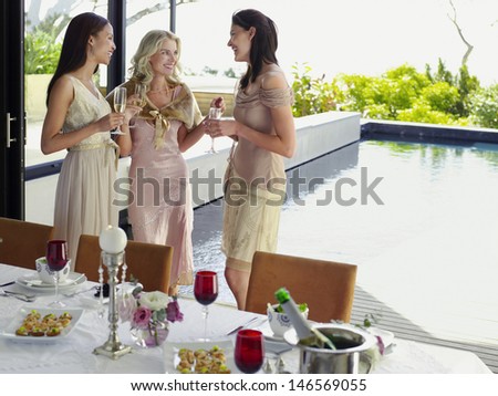Three young female friends with champagne flutes at dinner party