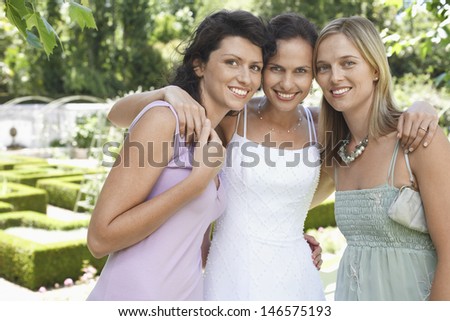 Portrait of beautiful bride with female friends standing together in garden