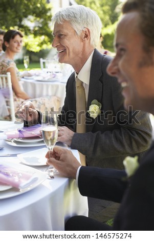 Happy middle aged man with guests in wedding reception