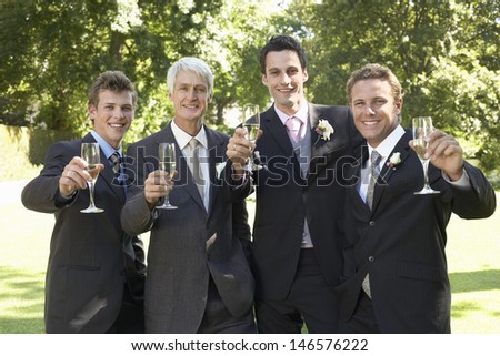 Portrait of happy four men toasting champagne flutes at wedding day