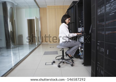 Full length side view of female technician working in server room