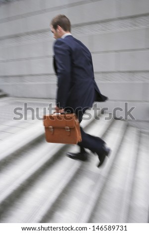 Full length side view of a businessman with briefcase ascending steps
