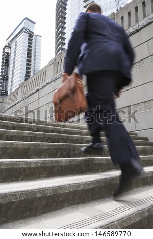 Full length rear view of a businessman with briefcase ascending steps