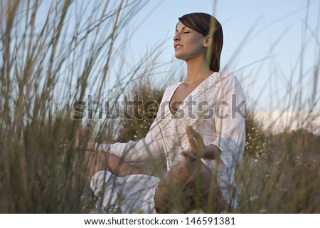 Low angle view of a young woman meditating on amid long grass