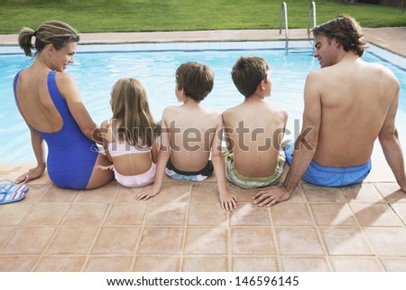 Rear view of a couple with three children sitting by pool