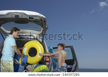 Father and son unloading car full of beach accessories