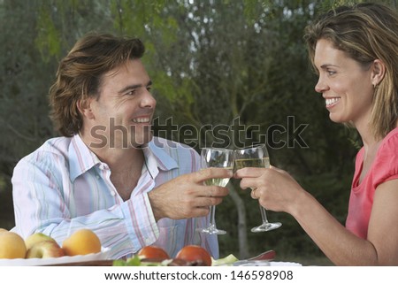 Smiling young couple toasting wineglasses at garden table