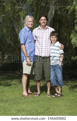 Full length portrait of grandfather; father and son standing under tree