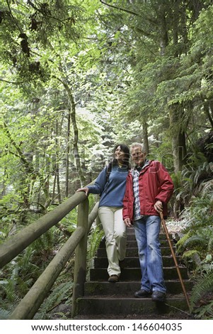 Full length of mature man and middle aged woman walking on forest stairs