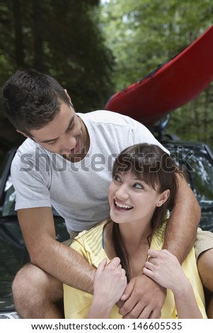 Man embracing young smiling woman from behind outdoors