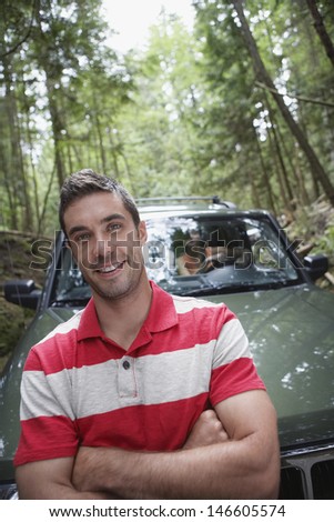Portrait of a young man in front of a car in the forest