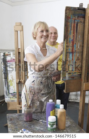 Two adult students painting at easel in art class