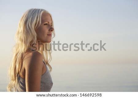 Side view of beautiful young woman standing on beach