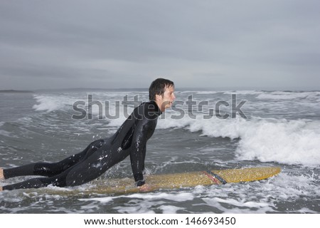 Side view of young man surfing in water at beach