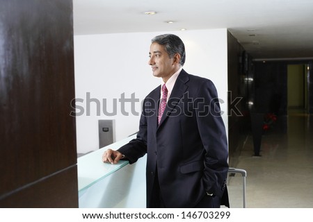 Middle aged businessman standing at check-in counter of hotel