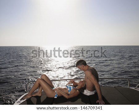 Loving couple relaxing at the edge of yacht by sea