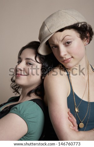 Portrait of beautiful young women standing back to back on colored background