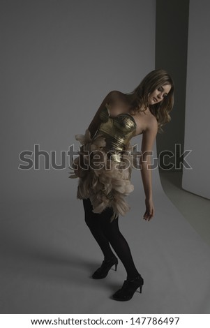 Full length of a female fashion model in gold dress with feathers