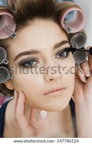 Closeup of a hand applying mascara to female model