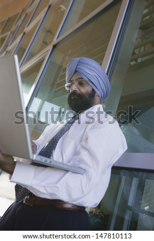 Low angle view of a serious Indian businessman using laptop