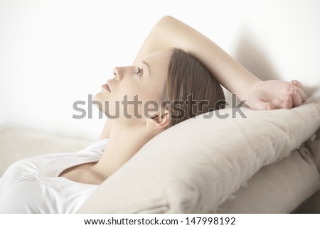Side view of young woman relaxing with hands behind head