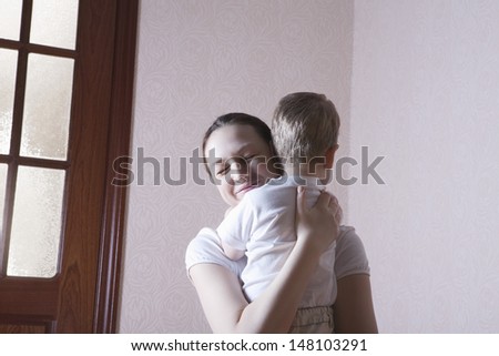 Happy mother hugging son at home