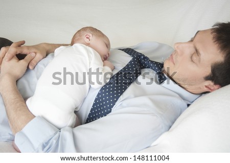 Two week newborn baby sleeping with father in bed