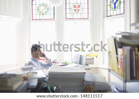 Side view of happy businessman using cell phone in home office