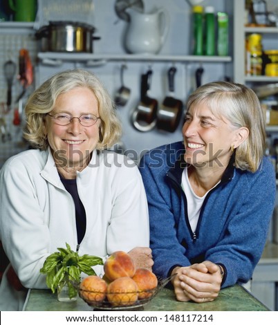 Smiling senior women leaning at kitchen counter