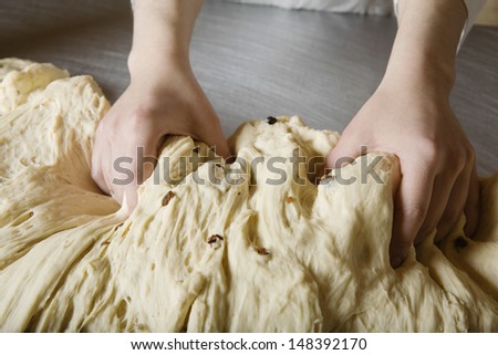 Closeup of baker\'s hands kneading bread dough in bakery