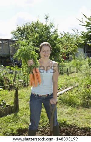 Portrait of smiling woman harvesting organic carrots in community garden