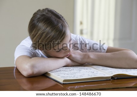 Relaxed teenage girl reading music sheet at desk