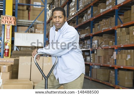 Portrait of a content worker leaning on trolley in distribution warehouse