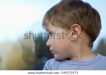 Cute little boy looking at reflection of self on glass