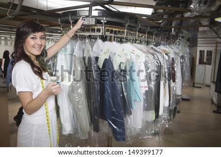 Portrait of young laundry owner with receipt checking clothes