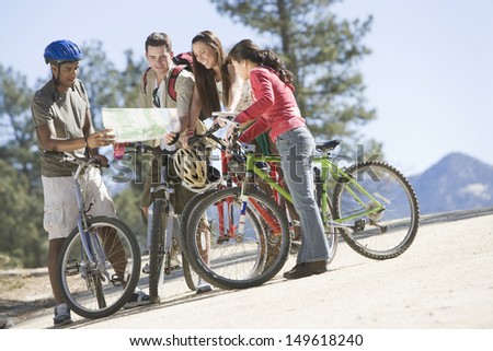 Group of multiethnic young friends with mountain bikes and map