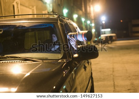 Professional photographer with telephoto lens in car