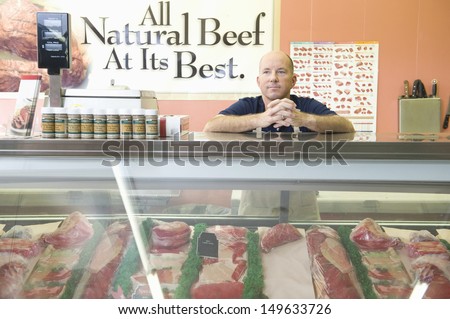 Supermarket employee standing at meat counter in supermarket
