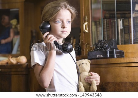 Cute blond girl with stuffed top using telephone at home