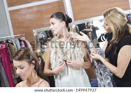 Multiethnic fashion model and female stylist in dressing room