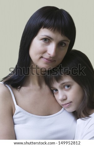 Portrait of a mother and daughter embracing against colored background