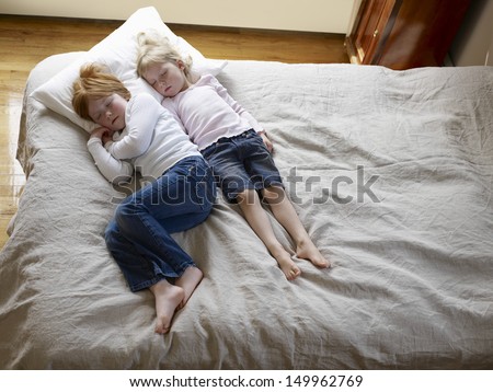 Elevated view of two little sisters sleeping in bed at home