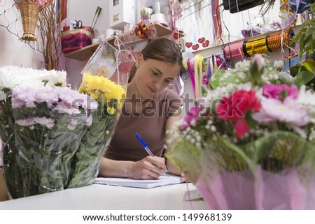 Young female florist at work with many flowers
