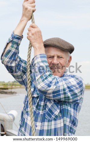 Closeup portrait of an elderly fisherman hauling rope in boat