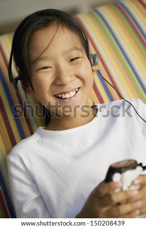 Happy little girl listening to music on MP3 player at home