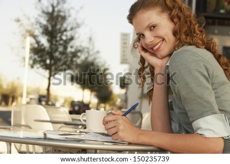 Side view portrait of young businesswoman holding pen at outdoor cafe