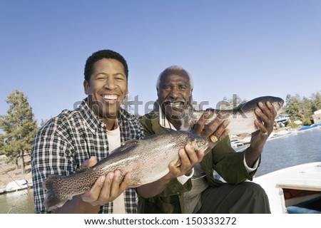 Portrait of happy father and son showing freshly caught fish