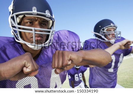 Determined young football players looking away while playing on field