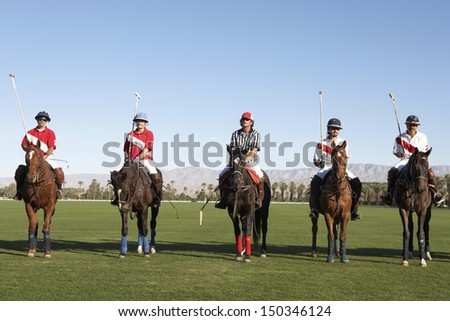 Polo players and umpire mounted on horses on field